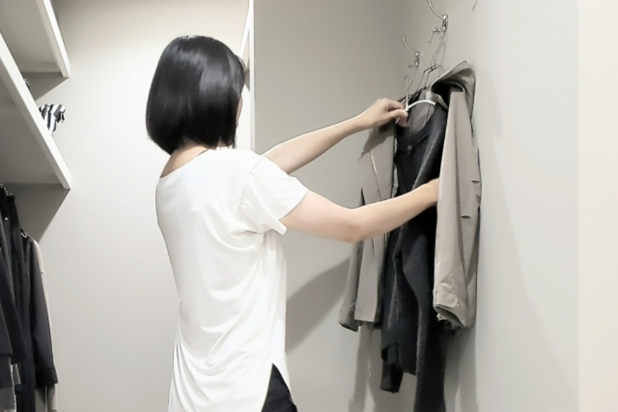 ハンガーの洋服を組み合わせてコーディネートを考える女性